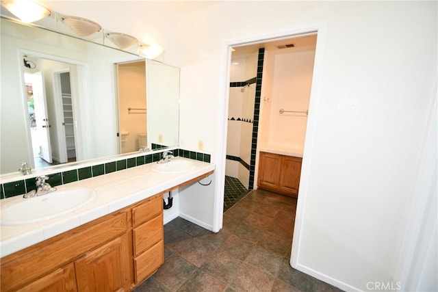 bathroom with tiled shower and vanity