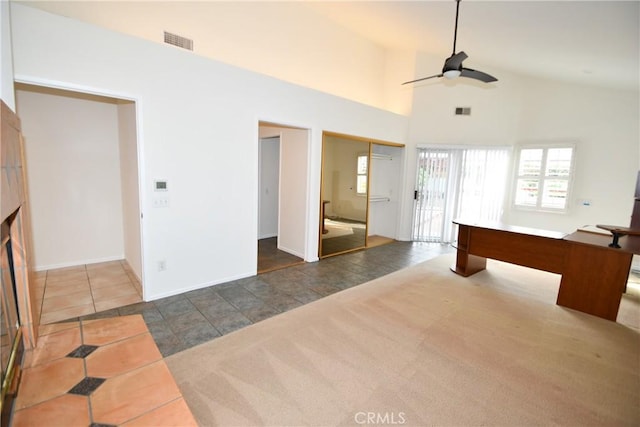 interior space with dark tile patterned flooring, ceiling fan, and high vaulted ceiling