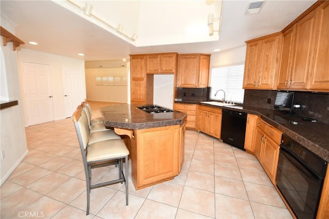 kitchen with decorative backsplash, sink, black appliances, a center island, and a breakfast bar area