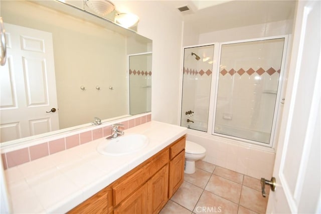 full bathroom featuring toilet, vanity, tile patterned floors, and enclosed tub / shower combo