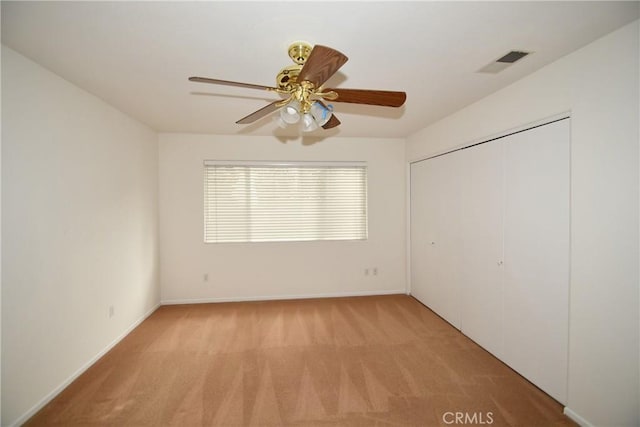 unfurnished bedroom featuring ceiling fan, light carpet, and a closet