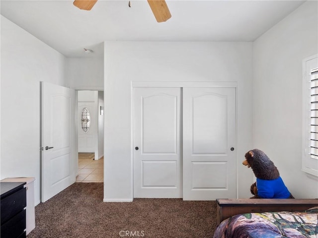 bedroom with ceiling fan, a closet, and dark colored carpet