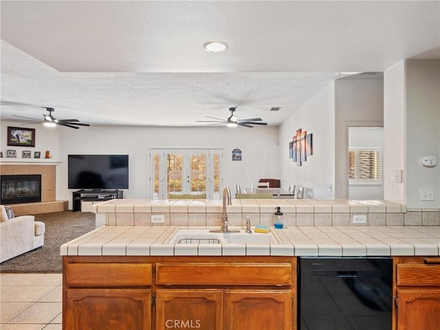 kitchen with tile countertops, dishwasher, a healthy amount of sunlight, and sink