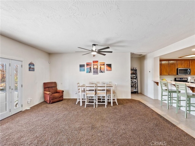 tiled dining room with ceiling fan and a textured ceiling