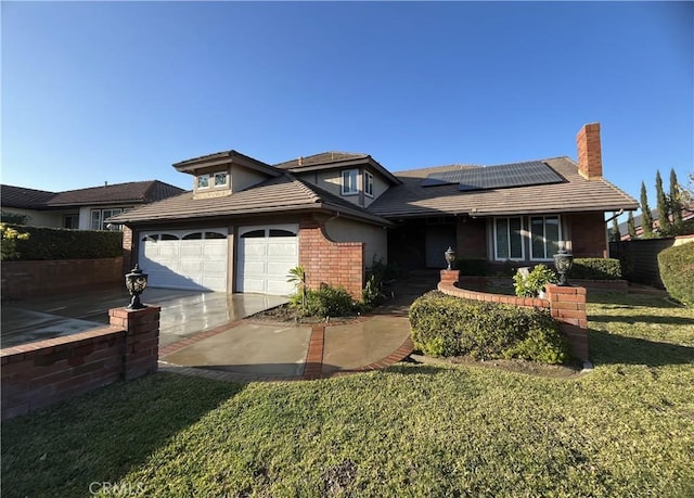 view of front facade with a front yard, solar panels, and a garage