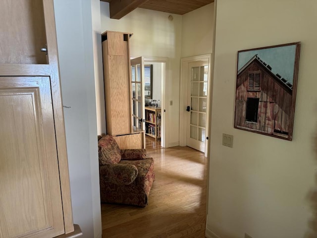 hall featuring beam ceiling and light hardwood / wood-style flooring