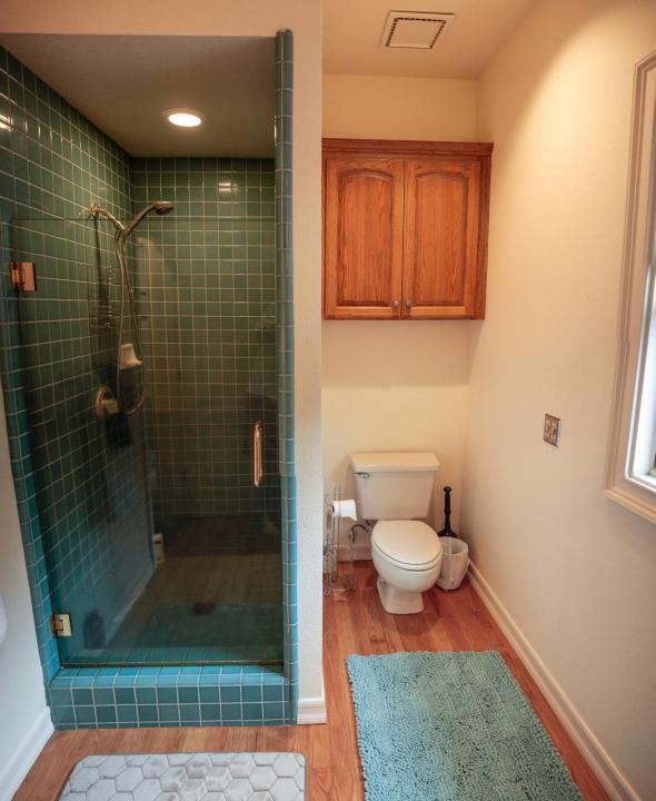 bathroom featuring wood-type flooring, an enclosed shower, and toilet