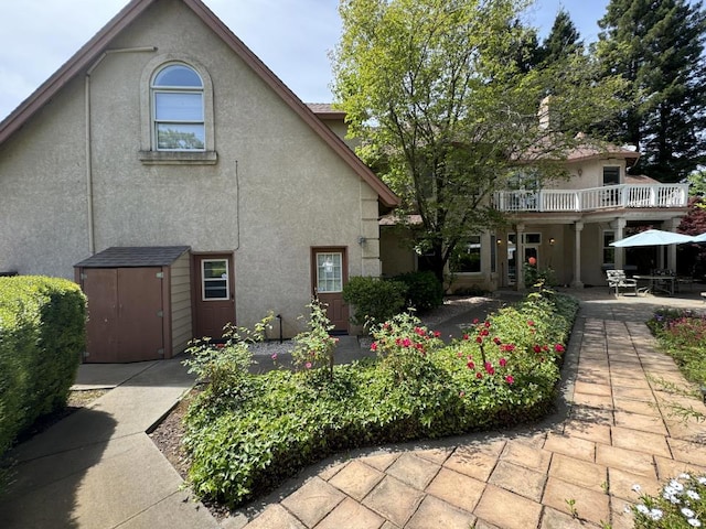 back of property with a patio area, a balcony, and a storage unit