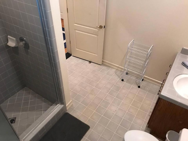 bathroom with toilet, vanity, a shower with door, and tile patterned floors