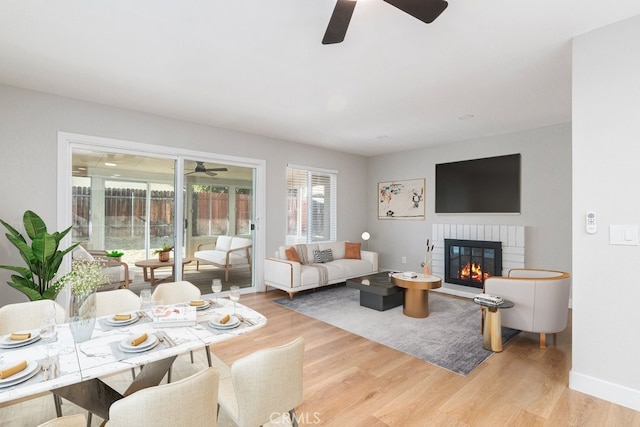 living room with a fireplace, ceiling fan, and light hardwood / wood-style flooring