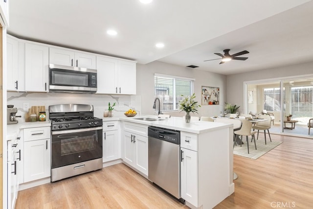 kitchen with white cabinets, light hardwood / wood-style floors, and appliances with stainless steel finishes