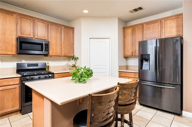 kitchen featuring a breakfast bar, light tile patterned floors, a kitchen island, and appliances with stainless steel finishes