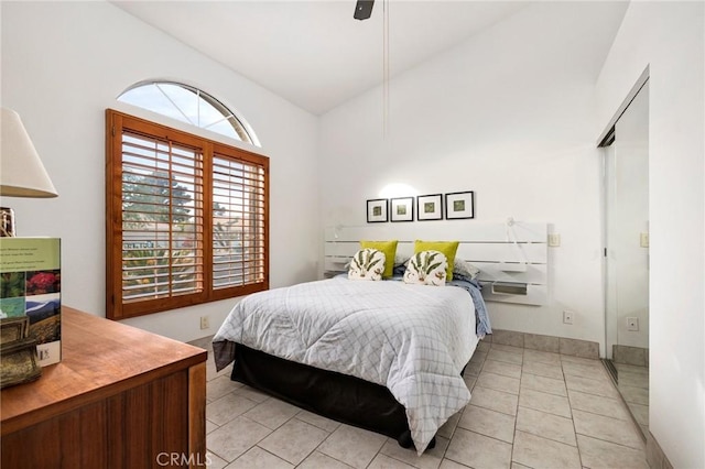 tiled bedroom with ceiling fan, a closet, and lofted ceiling