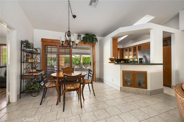 dining space with vaulted ceiling, light tile patterned flooring, and an inviting chandelier