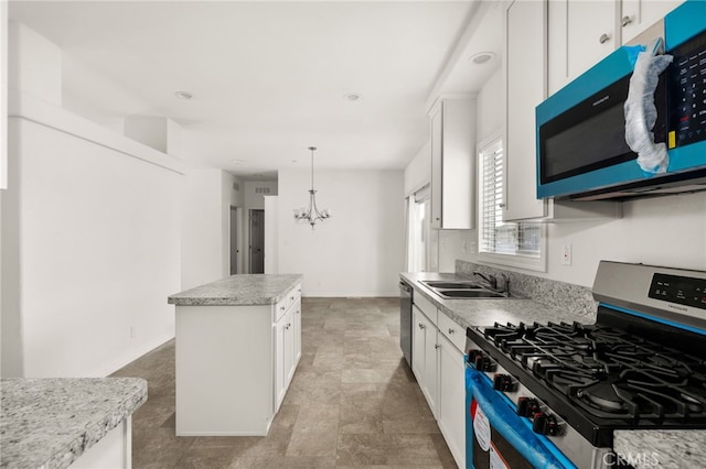 kitchen featuring sink, a center island, an inviting chandelier, white cabinets, and appliances with stainless steel finishes