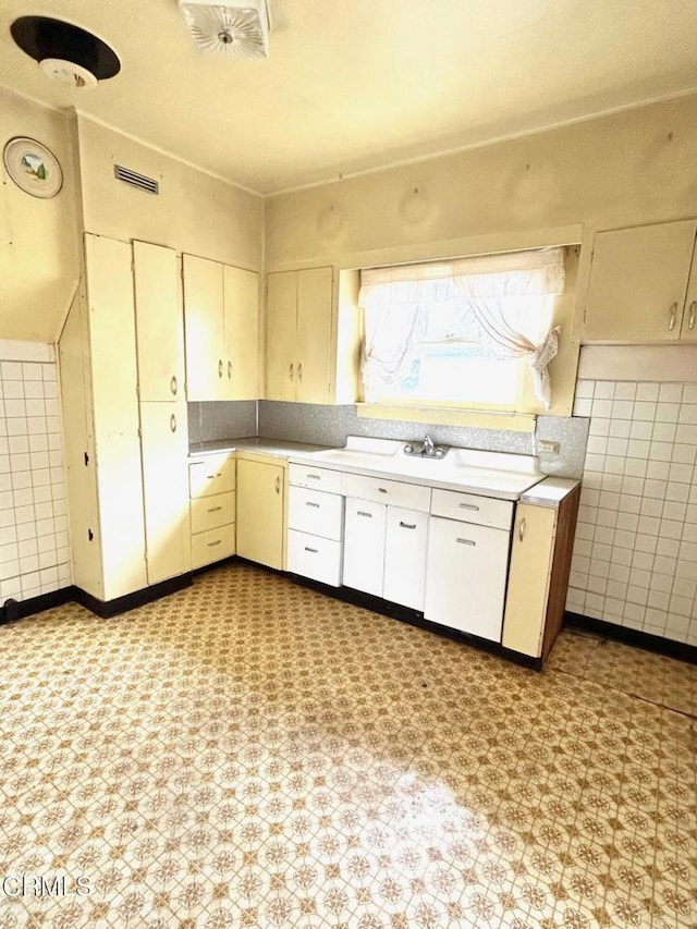 kitchen with tile walls and white cabinets