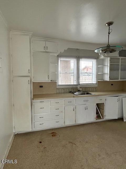 kitchen featuring decorative light fixtures, white cabinets, sink, and ornamental molding