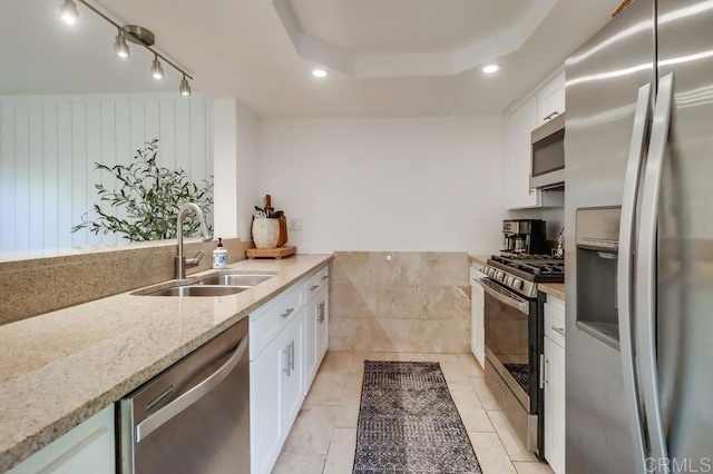 kitchen with light stone countertops, stainless steel appliances, sink, white cabinetry, and light tile patterned flooring