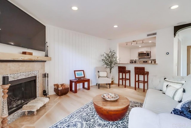 living room with wood walls, a fireplace, and light hardwood / wood-style flooring