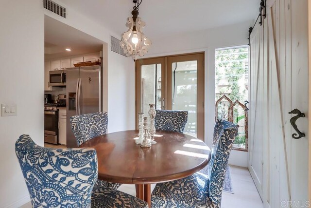 dining room featuring a barn door and an inviting chandelier