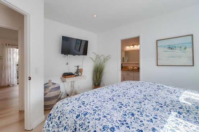 bedroom featuring connected bathroom and light hardwood / wood-style flooring