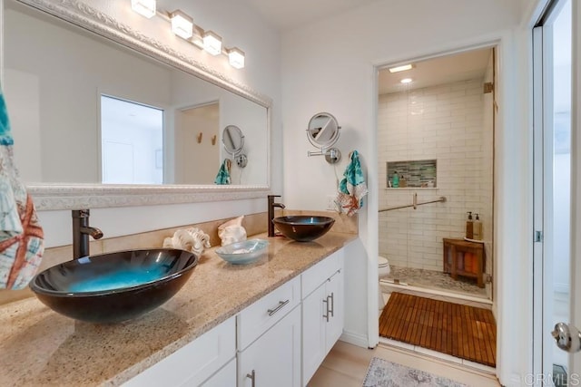 bathroom with tile patterned floors, vanity, toilet, and a tile shower