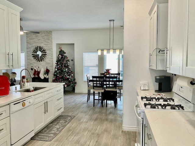 kitchen with white appliances, decorative light fixtures, white cabinetry, and sink