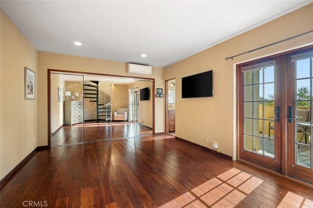 empty room with hardwood / wood-style floors, french doors, and a wall mounted air conditioner