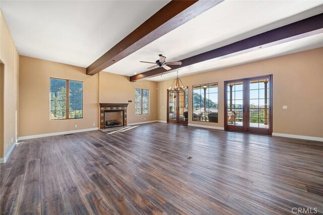 unfurnished living room with french doors, beamed ceiling, ceiling fan with notable chandelier, and dark hardwood / wood-style floors