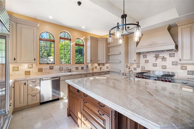 kitchen with stainless steel dishwasher, hanging light fixtures, custom range hood, sink, and light stone counters