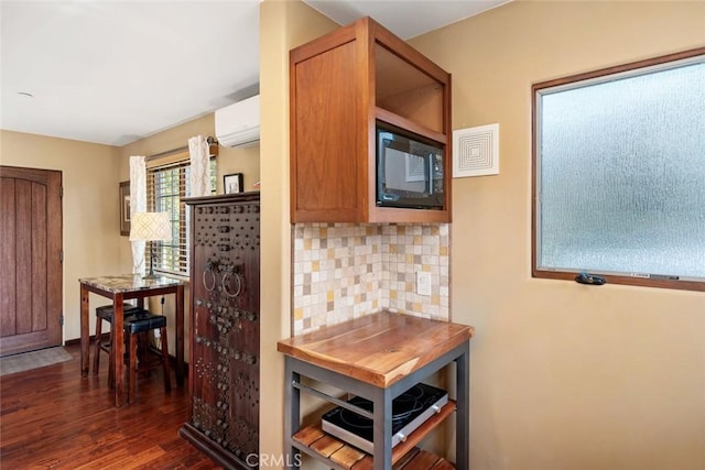 kitchen featuring black microwave, a wall mounted AC, decorative backsplash, and dark hardwood / wood-style floors