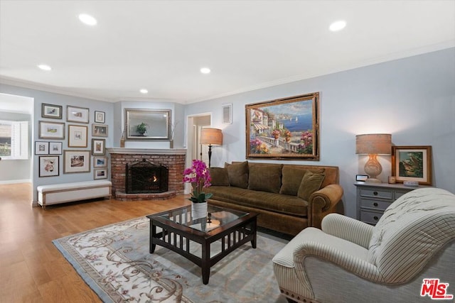 living room with a brick fireplace, ornamental molding, and light hardwood / wood-style floors