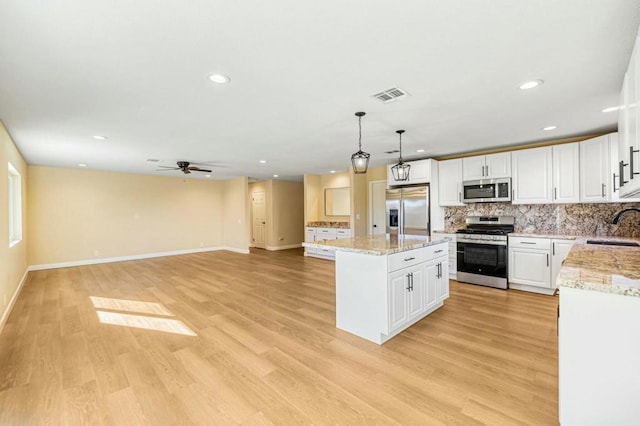 kitchen with a kitchen island, pendant lighting, sink, white cabinetry, and appliances with stainless steel finishes