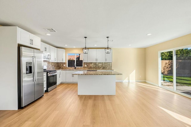 kitchen with white cabinetry, stainless steel appliances, decorative backsplash, pendant lighting, and light stone counters