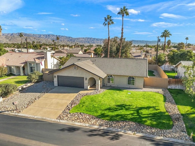 single story home featuring a front yard, a mountain view, and a garage