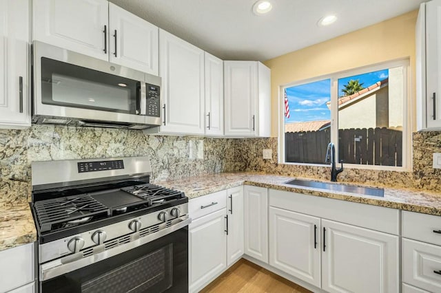 kitchen featuring white cabinets, appliances with stainless steel finishes, sink, and light stone counters