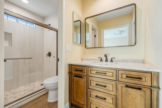 bathroom with hardwood / wood-style flooring, toilet, vanity, and a shower with door