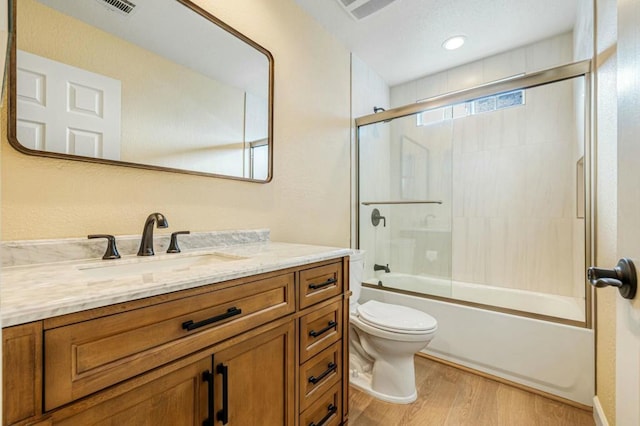 full bathroom with toilet, enclosed tub / shower combo, wood-type flooring, and vanity