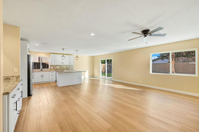 kitchen featuring pendant lighting, white cabinets, backsplash, ceiling fan, and light hardwood / wood-style flooring