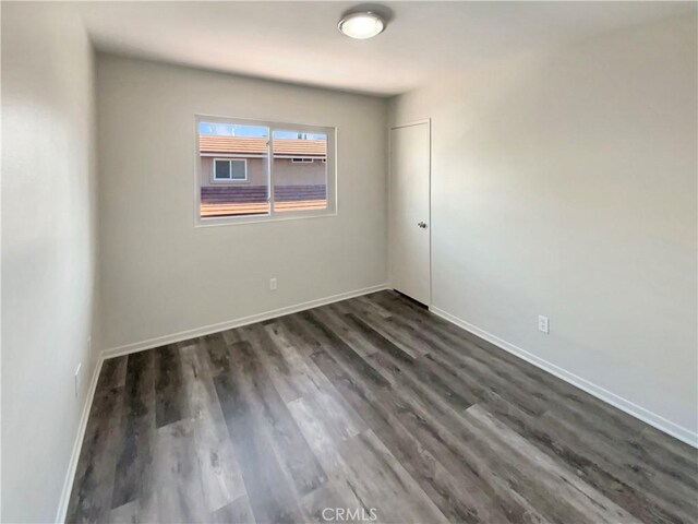 unfurnished room with baseboards and dark wood-style floors