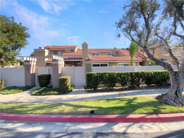view of front of home with stucco siding, a gate, a fenced front yard, and a chimney