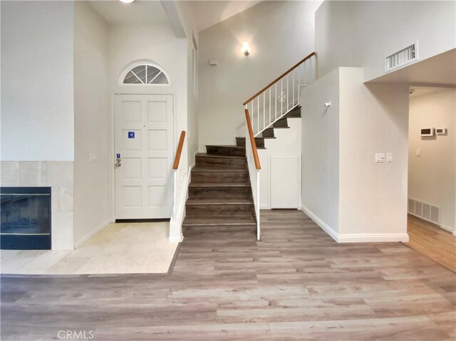 foyer entrance with wood finished floors, baseboards, stairs, and visible vents