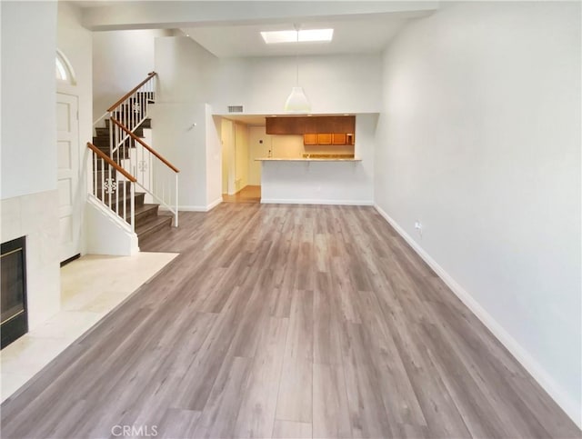 unfurnished living room featuring high vaulted ceiling, a fireplace, and light hardwood / wood-style flooring