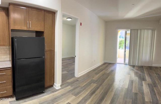 kitchen featuring black fridge, hardwood / wood-style floors, and backsplash