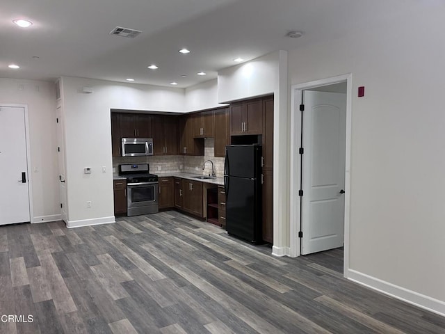 kitchen with sink, appliances with stainless steel finishes, hardwood / wood-style floors, dark brown cabinetry, and decorative backsplash