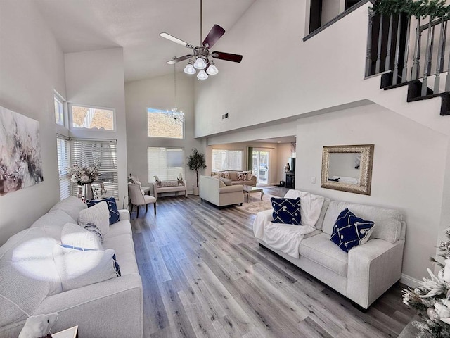 living room featuring hardwood / wood-style floors, ceiling fan with notable chandelier, and high vaulted ceiling