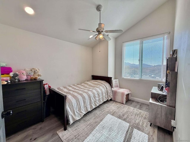 bedroom with light hardwood / wood-style flooring, vaulted ceiling, and ceiling fan