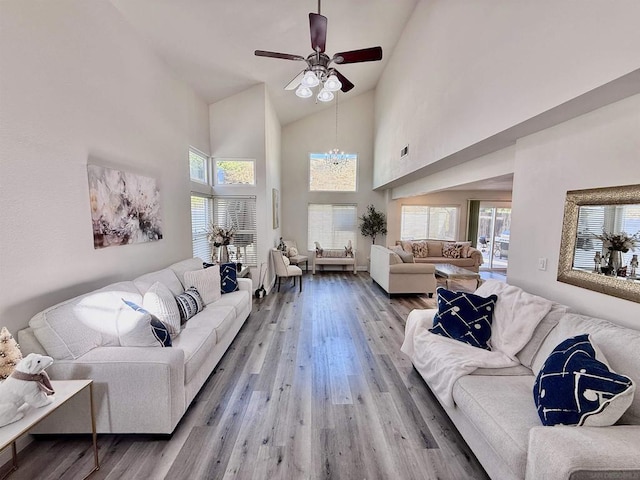 living room featuring high vaulted ceiling, ceiling fan with notable chandelier, and hardwood / wood-style flooring