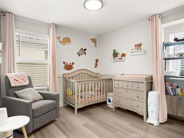 bedroom featuring a nursery area and light hardwood / wood-style floors