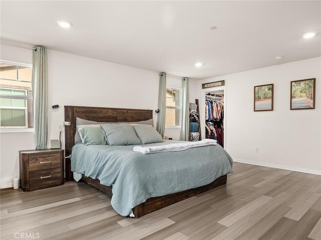 bedroom featuring light wood-type flooring, a walk in closet, and a closet